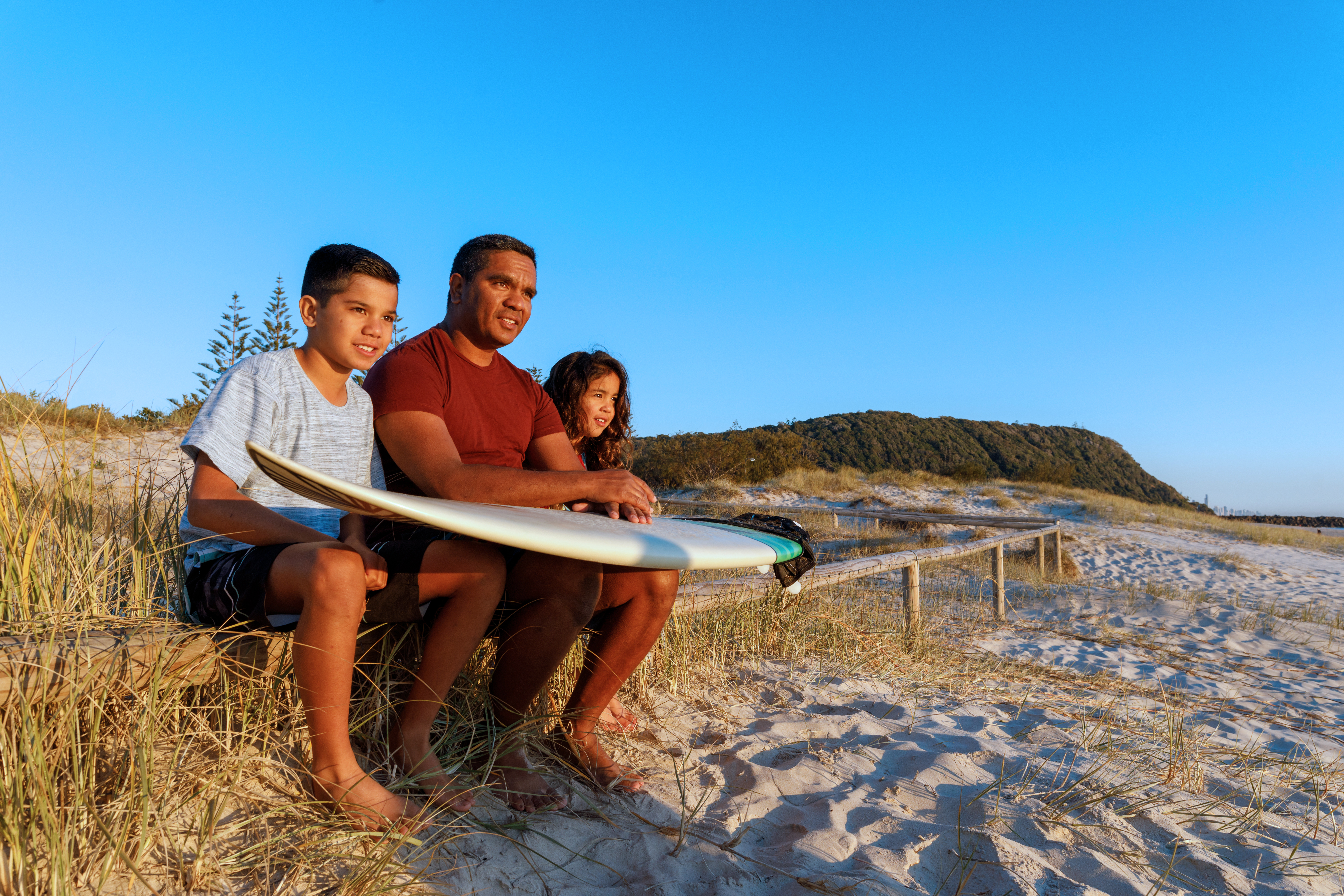 Father and two kids in the beach with surf board
